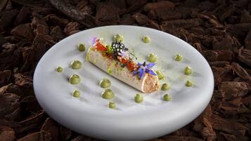 A dessert on a white plate with green dots and a chocolate background.