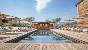 A pool area with wooden deck, lounge chairs, and umbrellas. - Jiva Hill Resort - Genève (Crozet)