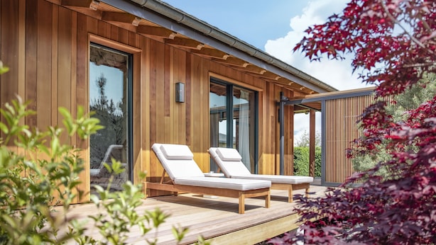 A modern wooden building with two lounge chairs on an outdoor deck. - Jiva Hill Resort - Genève (Crozet)