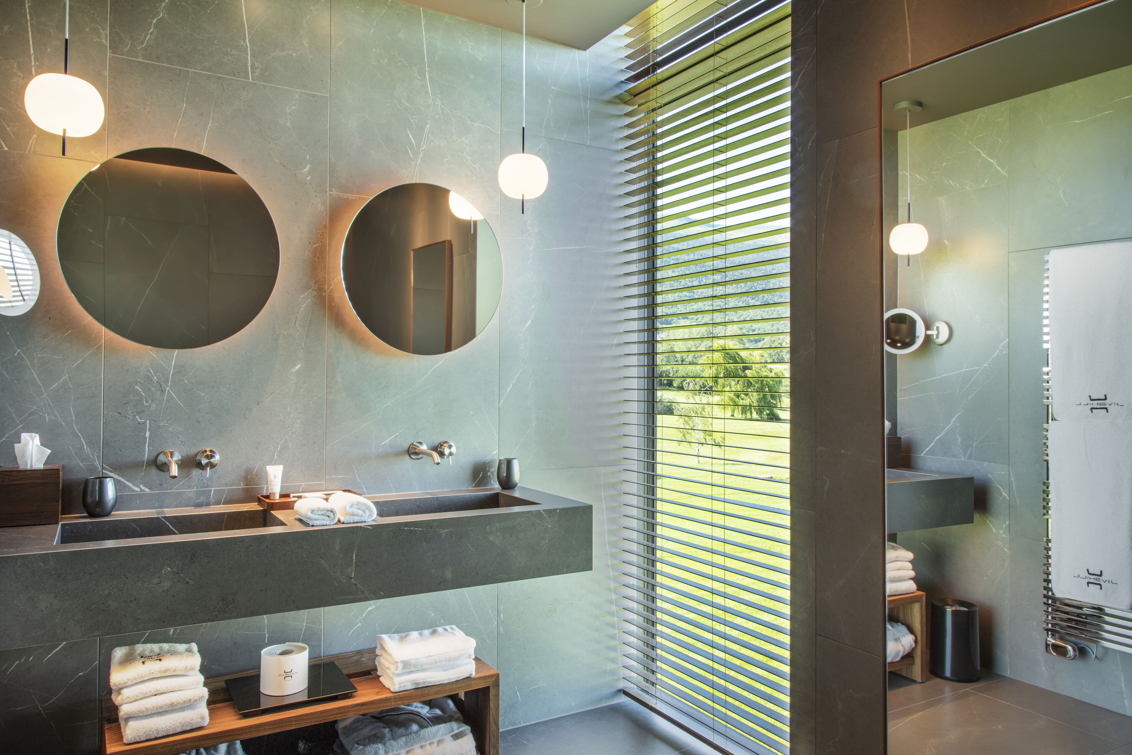 A modern bathroom with a large mirror, two sinks, and a glass shower enclosure.