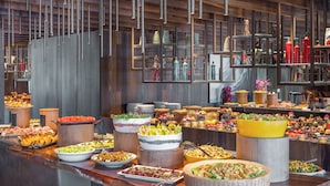 A buffet with various food items and drinks, including salads, fruits, and pastries, displayed on wooden stands and tables. - Jiva Hill Resort - Genève (Crozet)