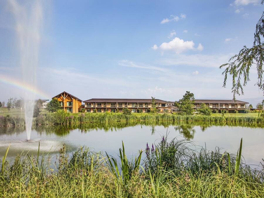 Ein Hotel mit einem großen Gebäude und einem Teich mit einer Fontäne.