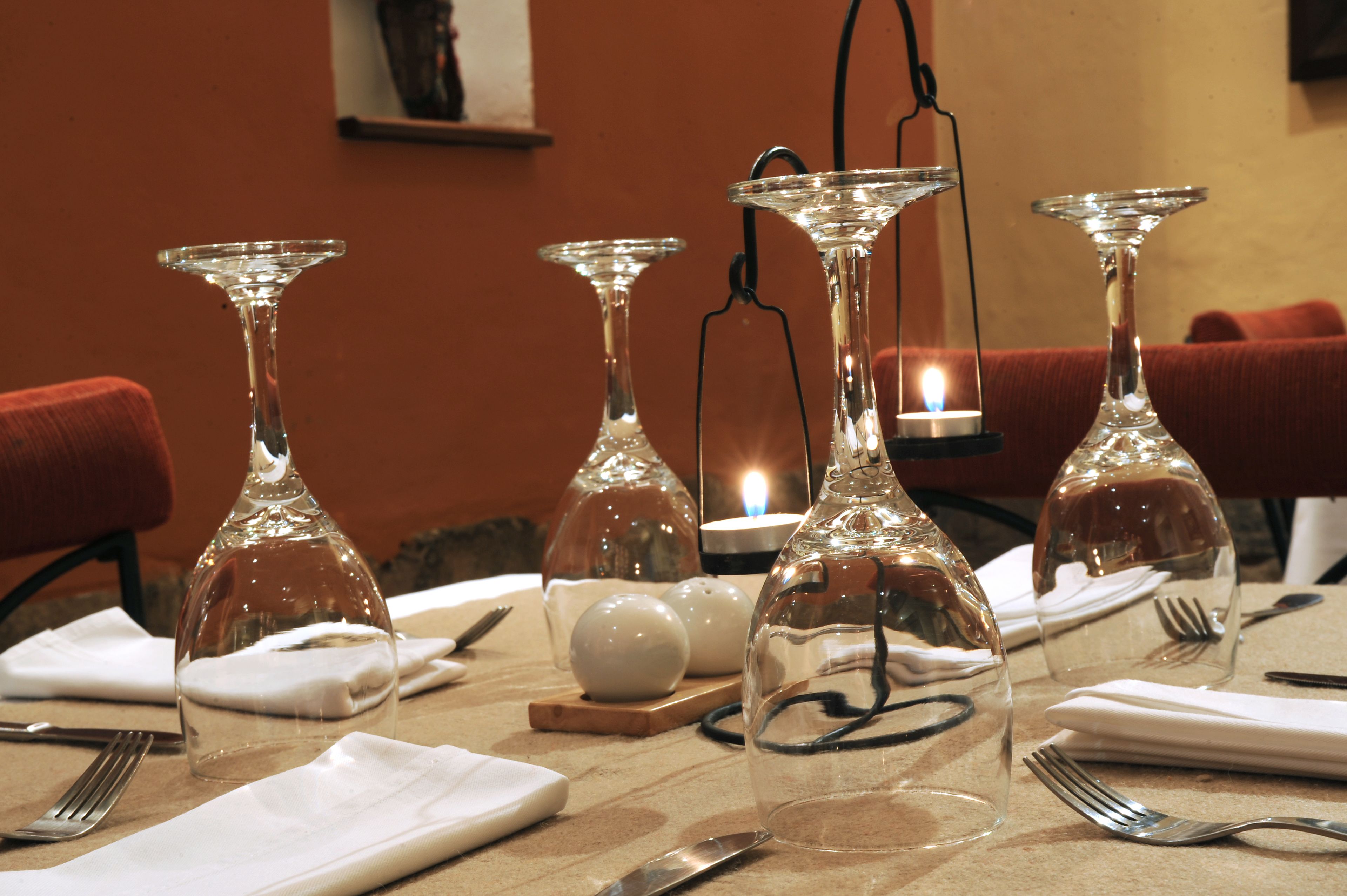 A dining table set with multiple wine glasses, a candle, salt and pepper shakers, and cutlery.