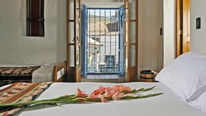 A hotel room with a bed, a wooden door leading outside, and a view of the outside. - Casa San Blas Boutique Hotel (Cusco)