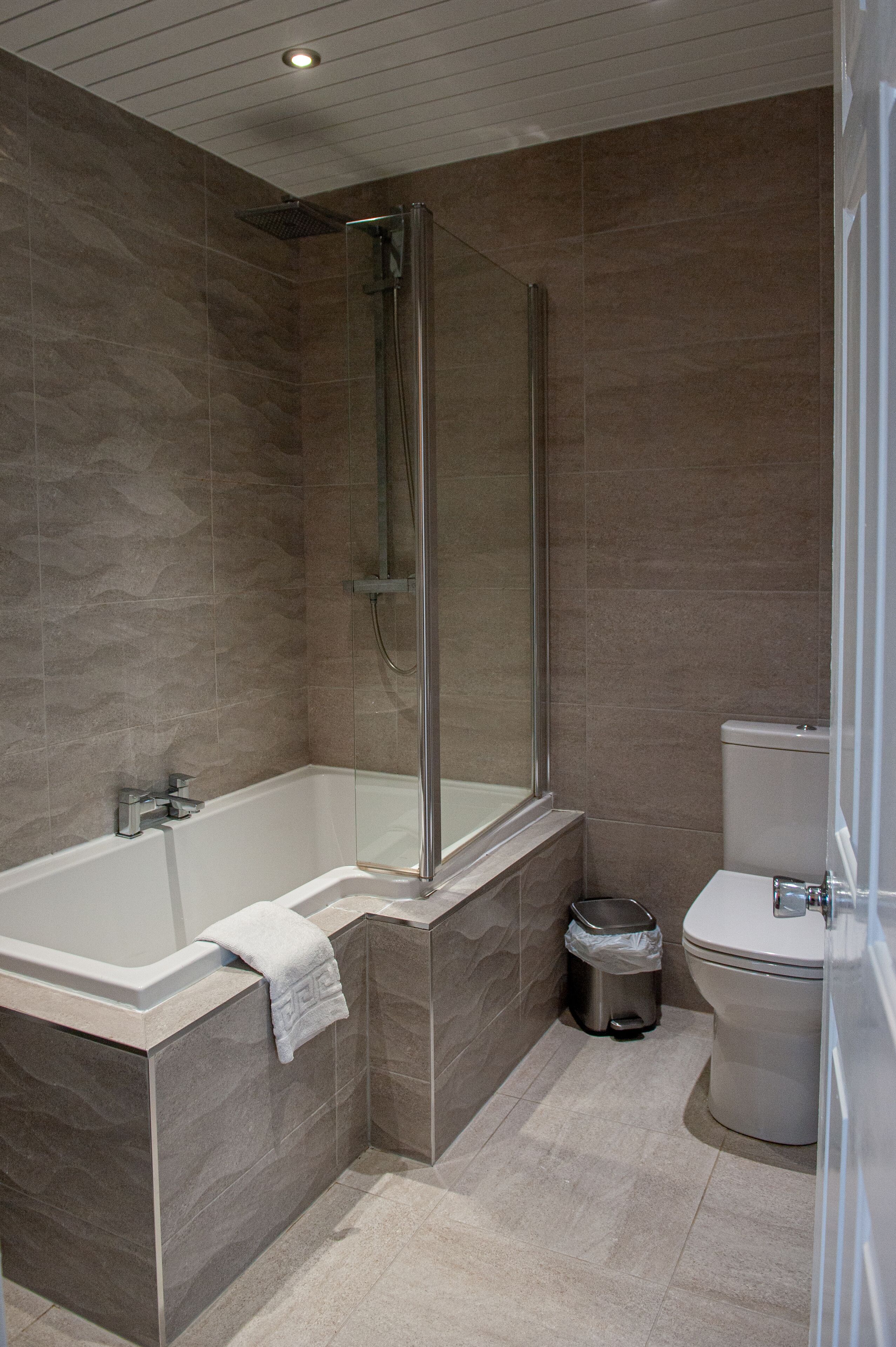 Un baño moderno con ducha envuelta en vidrio, inodoro independiente y bañera.