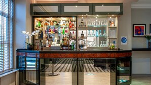 A bar area with shelves of various liquor bottles, a cash register, and a patterned floor.