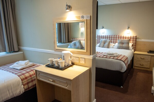 A hotel room with two beds, a small desk with a mirror, and a tray with cups and a kettle.