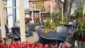 An outdoor patio area with wicker furniture and potted plants.