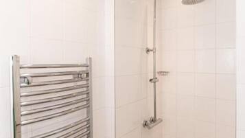 A small, modern bathroom with a walk-in shower, a towel rack, and a tiled floor.