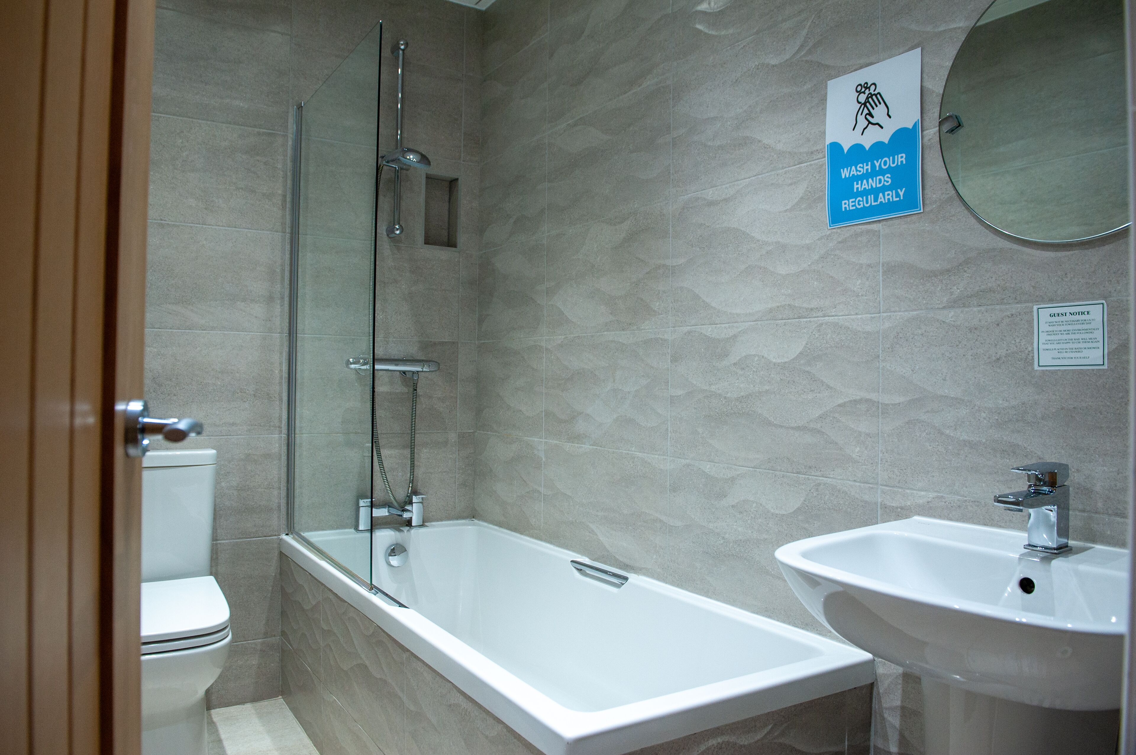Un baño moderno con ducha de vidrio, una bañera blanca y un lavamanos.