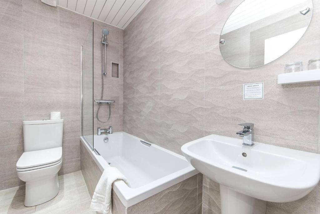 A modern bathroom with a toilet, a bathtub, and a sink.