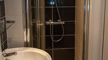 A modern bathroom with a glass-enclosed shower, a white sink, and a towel hanging on the sink.
