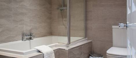 A modern bathroom with a glass-enclosed shower, a freestanding bathtub, and a toilet.