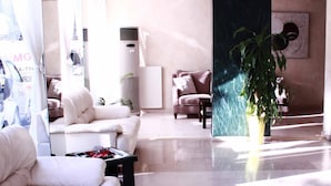 Un vestíbulo moderno con un sofá blanco, una mesa de centro y una planta en maceta.