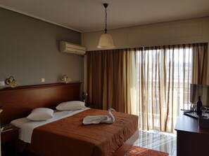 A hotel room with a large bed, a desk, a TV, and a window with curtains.