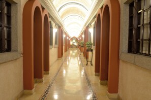 A long, well-lit corridor with arched ceilings and tiled flooring. - Hotel Arcangel  (Puebla)