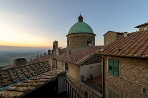 Um edifício histórico com cúpula e um campanário, rodeado por edifícios de pedra tradicionais com telhados de azulejos.