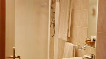 A bathroom with a glass-enclosed shower, a toilet, and a sink.