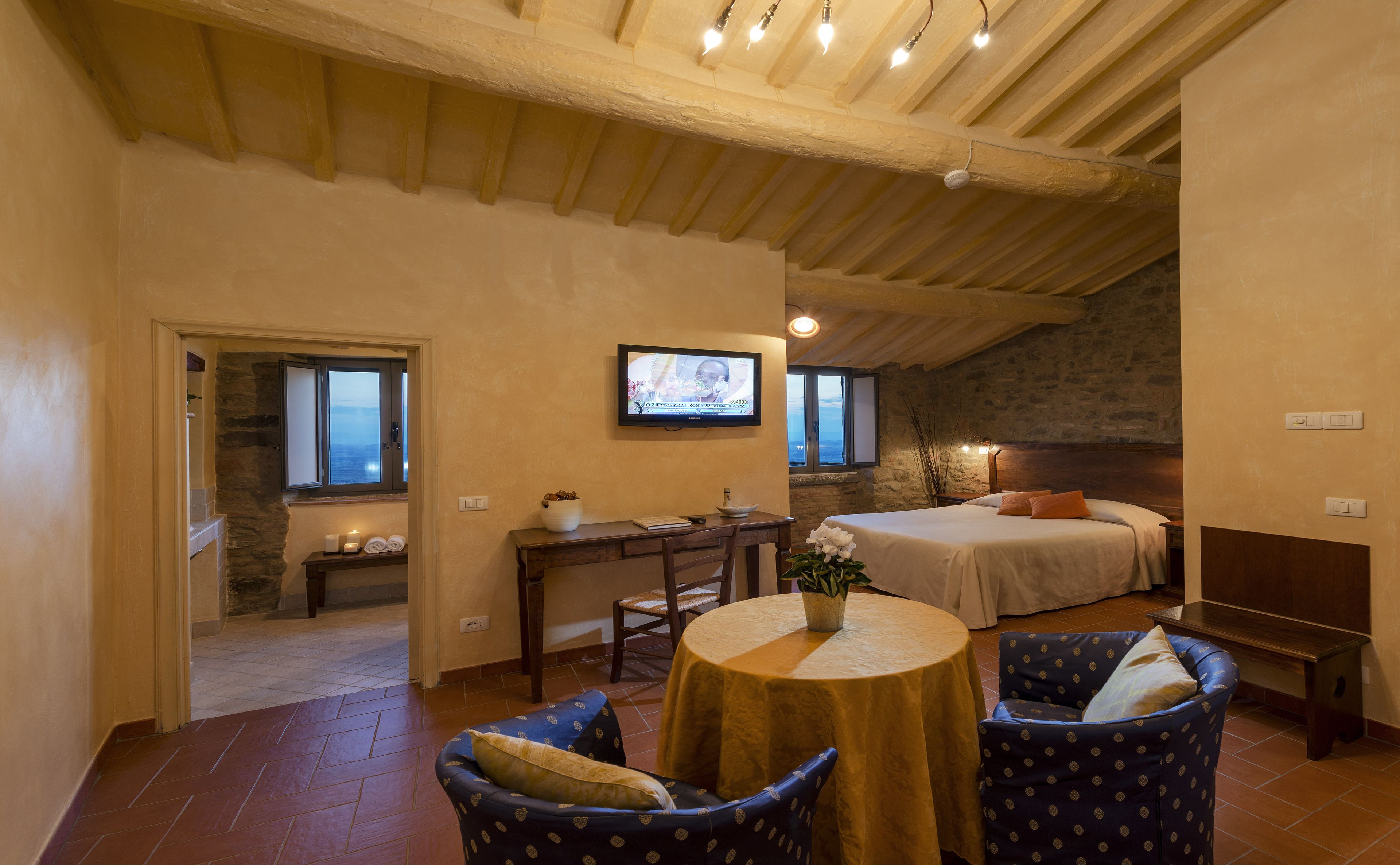 Una habitación acogedora con cama, escritorio, silla y una mesa con un florero.