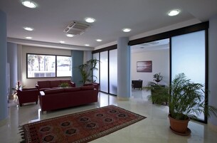 A spacious lobby with a red sofa, a patterned rug, and potted plants.