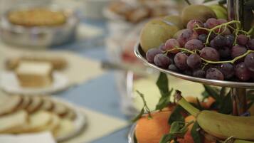 Un tavolo da buffet con diversi cibi, tra cui frutta e pasticceria.