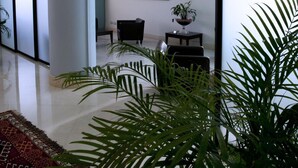 A modern interior with a large glass door leading to a room, a potted plant, and a framed picture on the wall. - Tiziano Hotel (Trapani)
