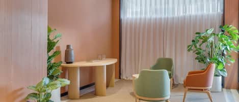 Een moderne kamer met een ronde tafel, twee stoelen en twee planten in potten.