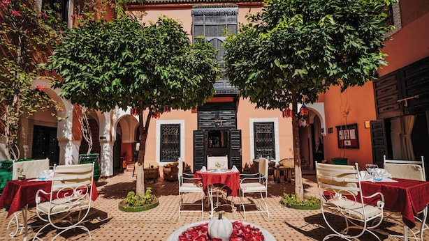 An outdoor patio with tables and chairs, a fountain, and trees.
