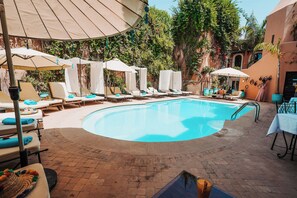 Una piscina al aire libre, sombrillas, sillones reclinables de piscina