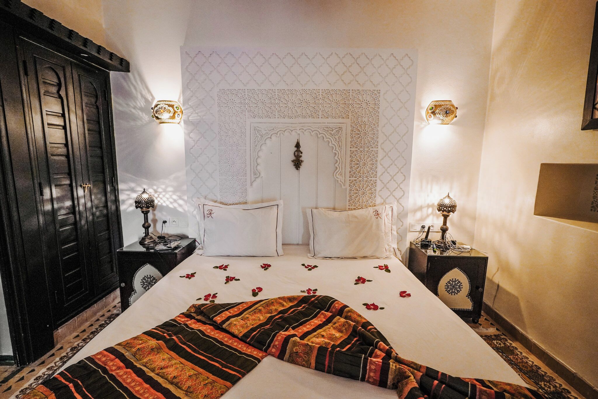 Un dormitorio con cama, dos mesitas de noche, un armario y paneles decorativos en la pared.