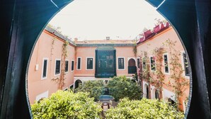 A courtyard with a central fountain, surrounded by buildings with arched doorways and windows.