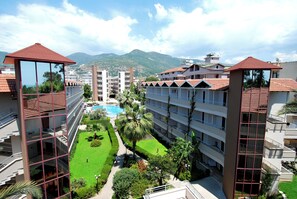 A hotel with multiple floors, a swimming pool, and a view of mountains. - Panorama (Alanya)