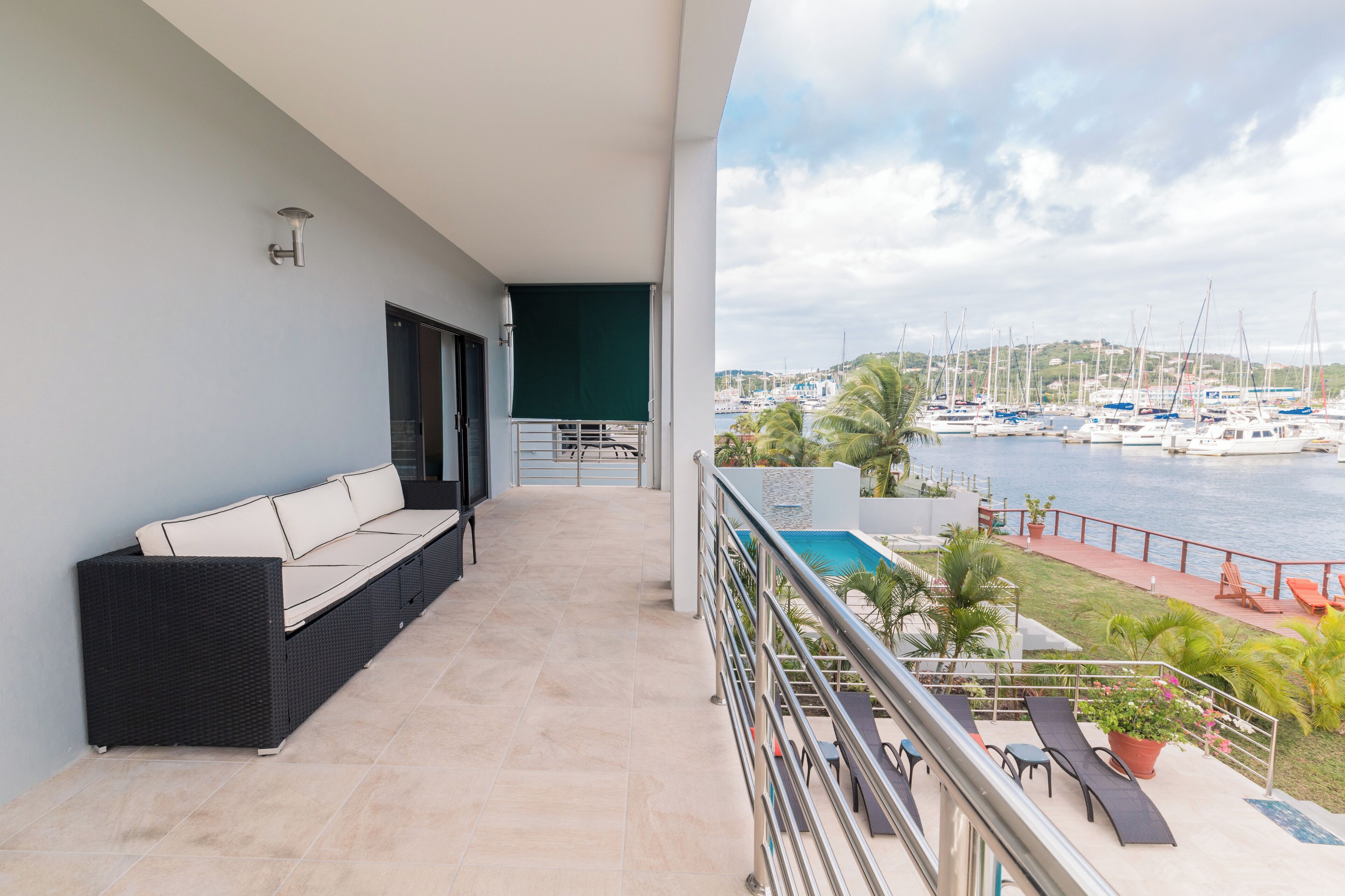 Un balcón con sofá, piscina y vistas a barcos.