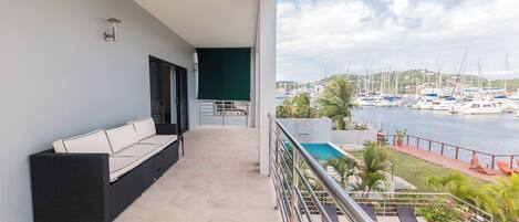Ein Balkon mit einer Sitzecke, einem Pool und Blick auf Boote.