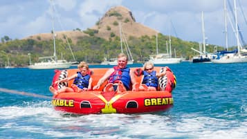 A red inflatable raft with the words "MABLE" and "GREAT" on it, floating on water with a mountainous background.