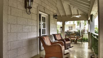 A covered porch with wicker rocking chairs and a ceiling fan.