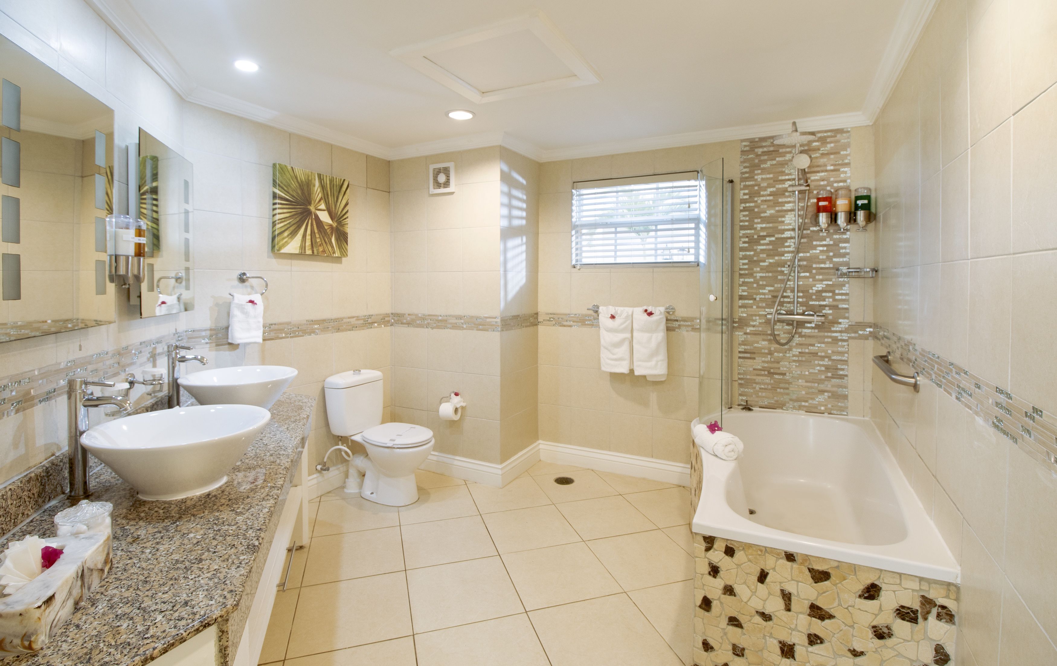 A modern bathroom with a large bathtub, two sinks, a toilet, and a shower area.