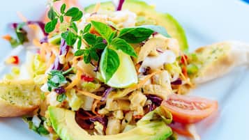 A plate of mixed salad with avocado, tomatoes, and herbs.