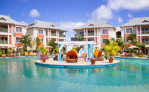A resort pool area with a circular water feature, lounge chairs, and a covered seating area. - Bay Gardens Beach Resort and Spa (Gros Islet)