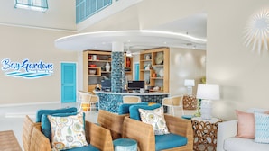 Una hall con mobili in vimini, una reception e un cartello con la scritta 'Bay-Gardens Beach Resort & Spa'.