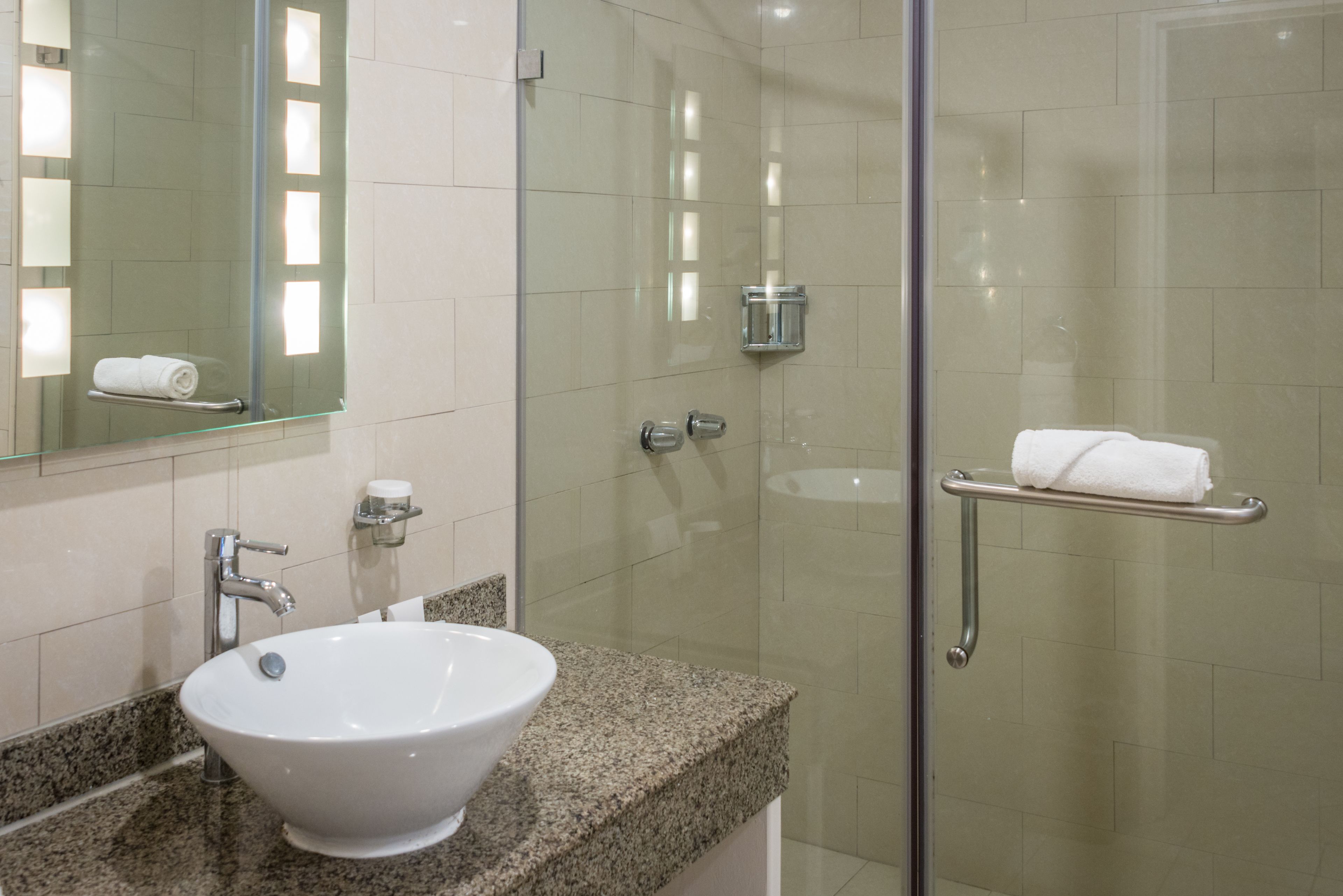 A bathroom with a glass-enclosed shower, a white sink, and a mirror.