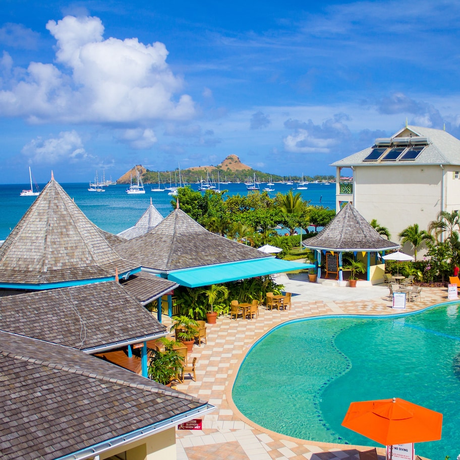 A resort with a swimming pool, beach view, and multiple buildings with distinct roofs.