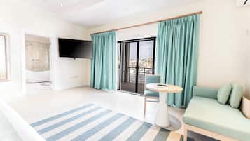 Un salon moderne comprenant un canapé, une petite table ronde, un téléviseur et une porte-fenêtre coulissante donnant sur un balcon.
