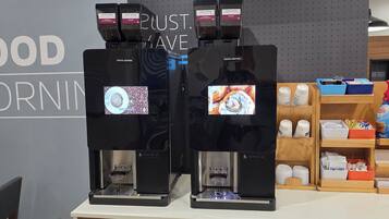 Dos máquinas de Costa Coffee con pantalla, dispensador de café y molinillo.