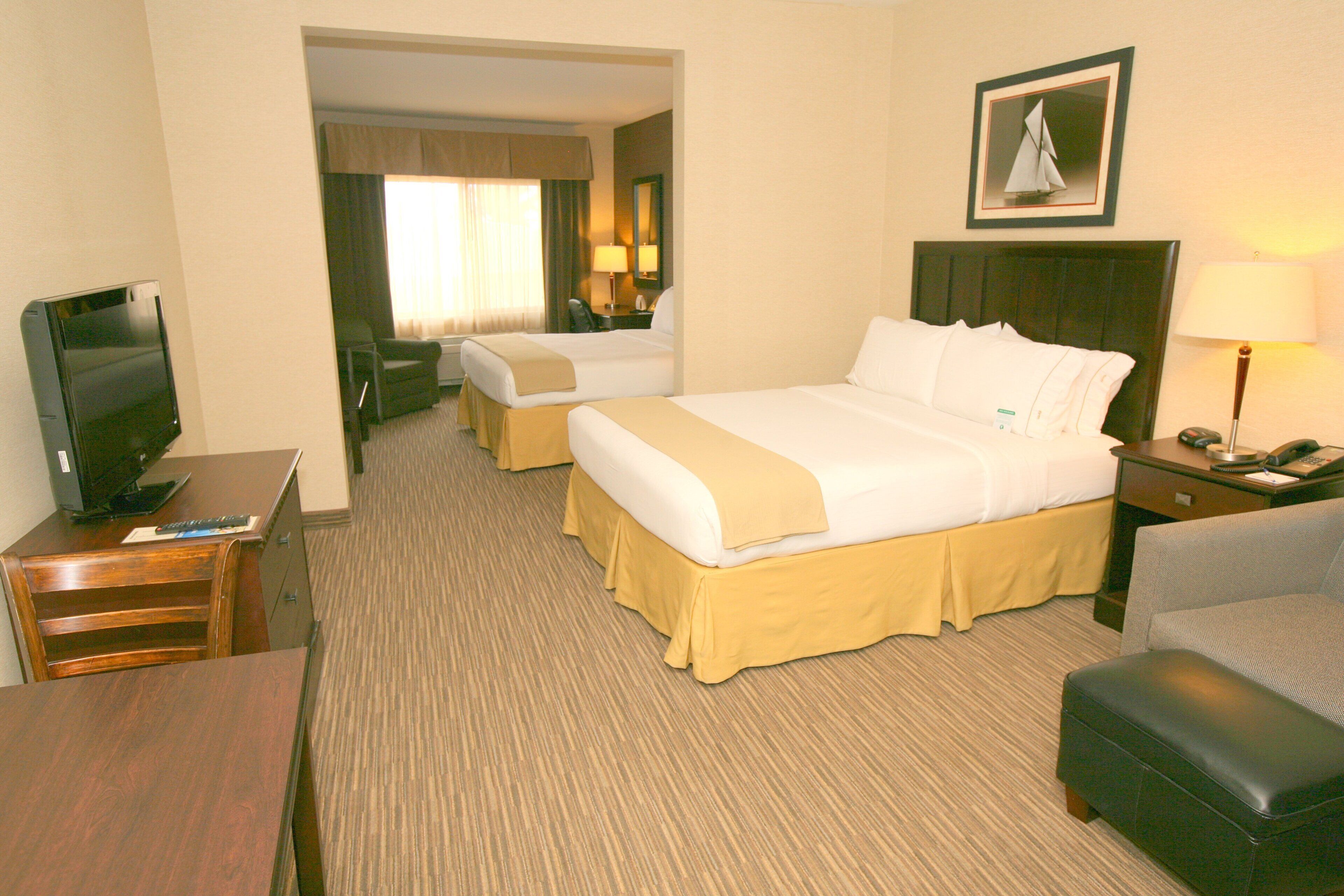 A hotel room with a bed, a desk, a television, a chair, and a lamp.