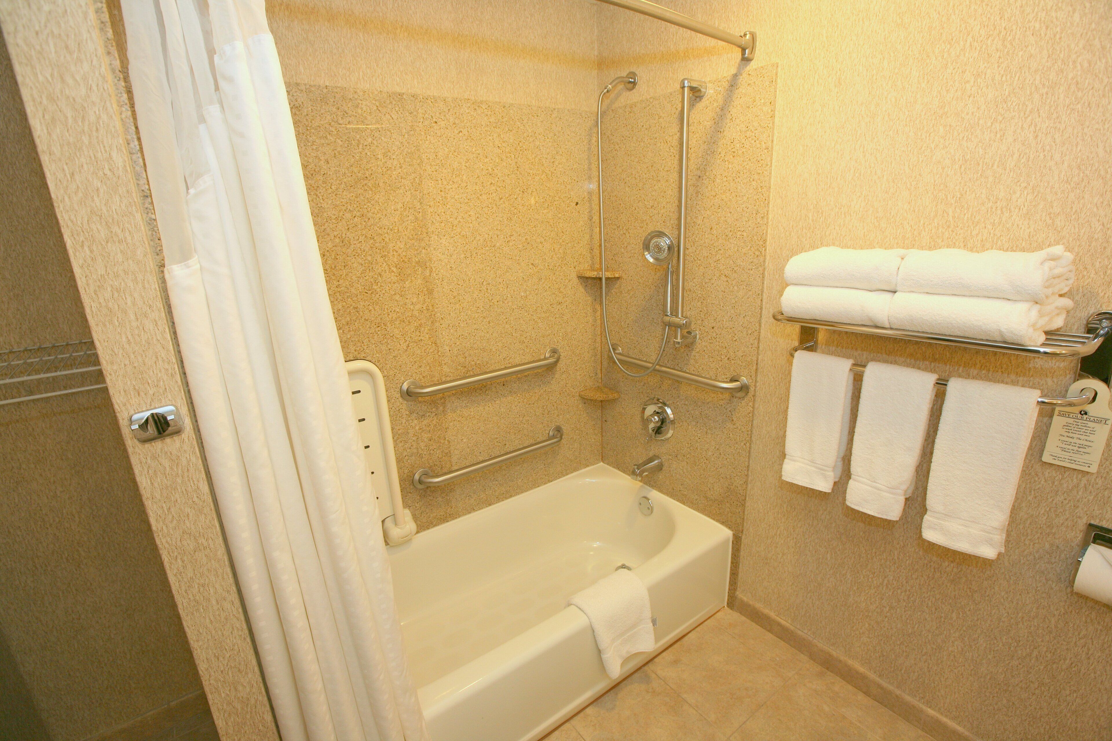 A bathroom with a bathtub, a shower, and a towel rack with towels.