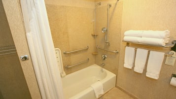 A bathroom with a bathtub, a shower, and a towel rack with towels.