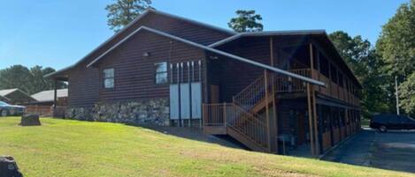 A two-story log cabin with a covered porch and a stone foundation.