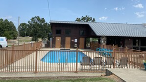Un área de piscina cercada con un edificio de madera al fondo.
