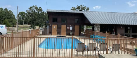 Ein Poolbereich mit Zaun und einem Holzgebäude im Hintergrund.